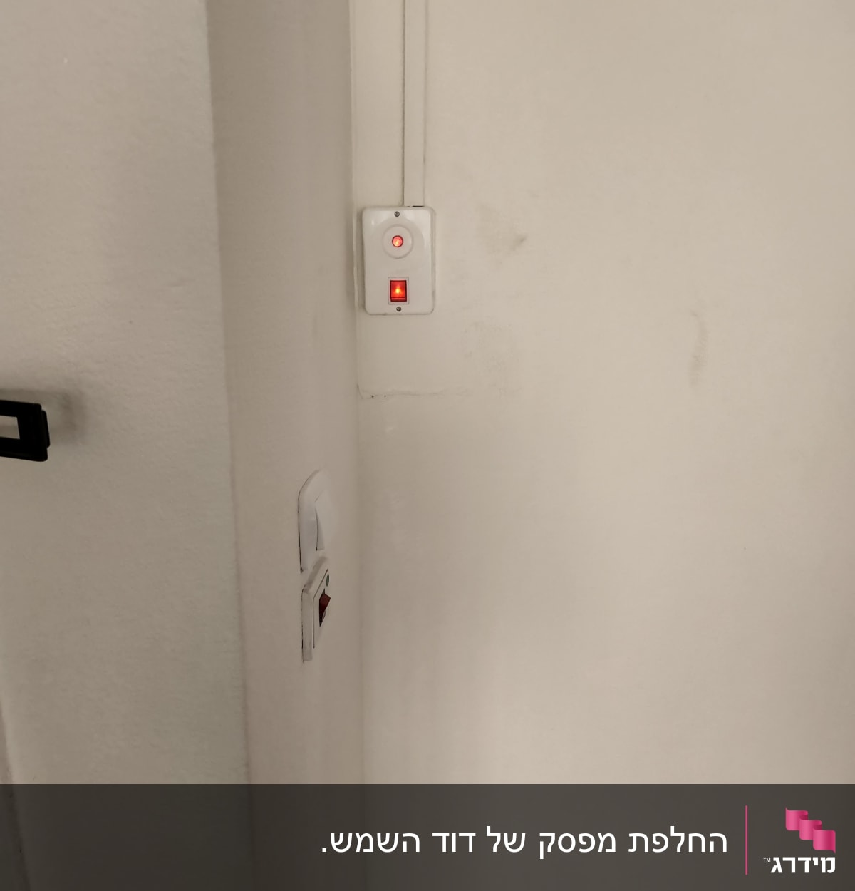 מתג דולק עם נורית חיווי אדומה על קיר לבן